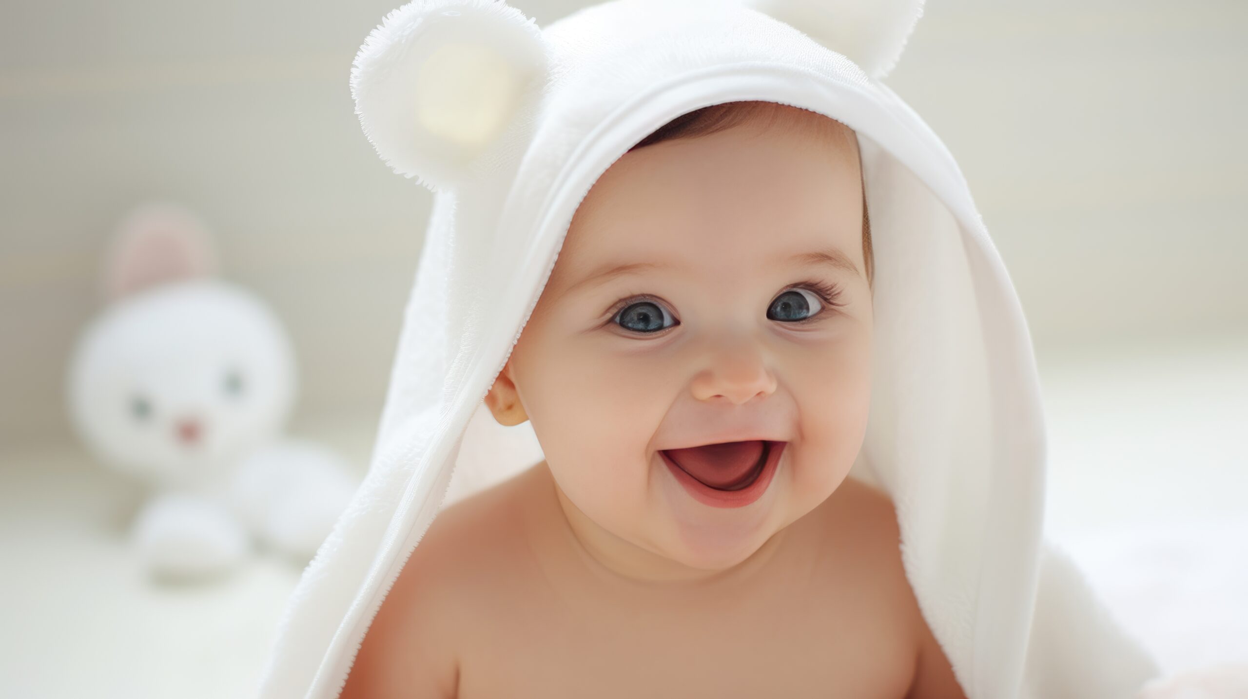 Cute_baby_with_a_towel_on_his_head_smiles_on_a_white_background.