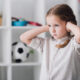close-up portrait-of-sad little-child-covering-ears-with-hands-and-looking-away